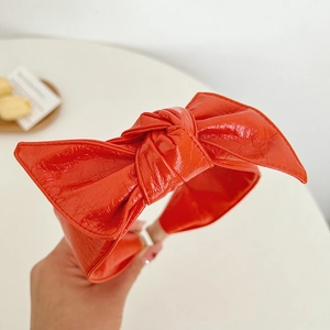 Detailed close-up showing the orange faux leather texture of the bow headband