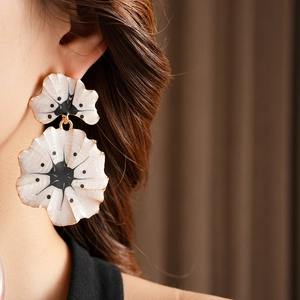 Gros plan de boucles d'oreilles vintage ginkgo blanc et or portées par un mannequin