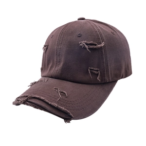 Détail d'une casquette de baseball vintage marron en coton avec des trous déchirés