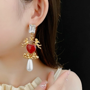 Detail of vintage heart earrings with gold cupid and pearl drop worn by model