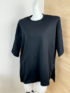 Detail of loose-fit black cotton t-shirt with drop shoulders and side split hem on mannequin