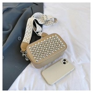 Khaki crossbody bag with silver rhinestones beside a smartphone for size scale