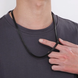 Close-up of hip hop black stainless steel curb chain necklace worn by a model on a grey tee