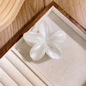 Elegant pearl white plumeria flower hair claw clip displayed on a premium jewelry tray