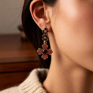 Close-up of vintage cross earrings with orange and deep red gemstones on model