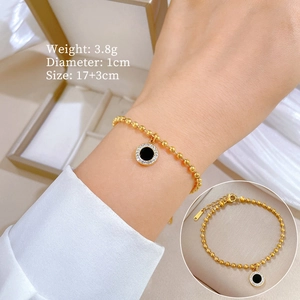 Gold beaded chain bracelet with black agate and crystal pendant shown on wrist