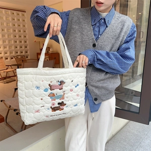 Detail of white quilted tote bag featuring cute dog embroidery and Have a nice day text