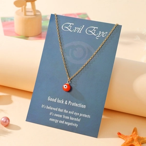 Detail of orange Evil Eye pendant necklace on blue gift card with shell decorations