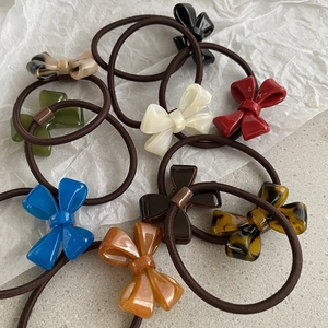Close-up of assorted acrylic bow hair ties in multiple colors on a white background