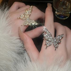 Detail of gold and silver butterfly rings with pearls and sparkling cubic zirconia on hand
