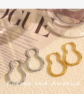 Detail view of gold and silver teardrop hoop earrings on a fashion magazine background