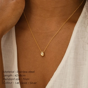 Detailed close-up of a 14K gold-plated teardrop pendant necklace worn by a model