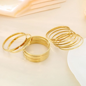 Polished gold titanium steel thin stacking bangles set in a minimalist multi-layered style