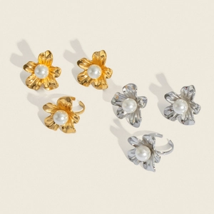 Detailed view of flower-shaped earrings and rings with large pearls in gold and silver