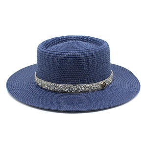 Detailed view of dark blue straw boater hat featuring silver rhinestone band and M logo
