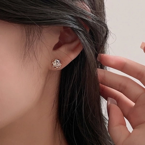 Elegant rose gold hollow rose stud earrings with zircon stone worn by a female model