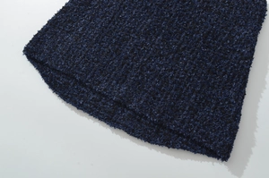 Vista macro della trama del tessuto bouclé blu scuro e del dettaglio dell'orlo della gonna