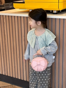 Close-up of a pink round children's handbag with a large bow and gold hardware detail