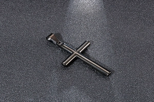Gros plan détaillé d'un pendentif croix en acier inoxydable poli sombre fini brillant