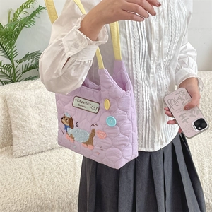 Close-up of light purple quilted tote bag with cute dog embroidery and yellow straps