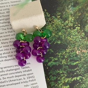 Detailed view of grape-shaped purple resin earrings with green leaf and gold hook