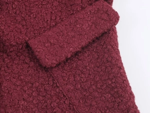 Detail of burgundy boucle wool fabric texture and pocket flap on the slim-fit jacket