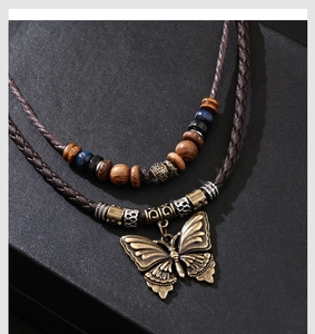 Détail du pendentif papillon en bronze vintage et perles en bois sur un collier à double rangée