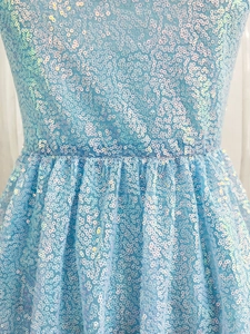 Macro detail of sky blue sequin fabric with iridescent luster on a cocktail party dress
