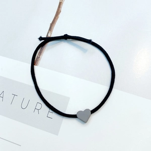 Close-up of black elastic hair tie with a minimalist grey heart-shaped resin charm