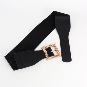 Detail of black elastic belt featuring a gold square buckle with rhinestone leaf accents