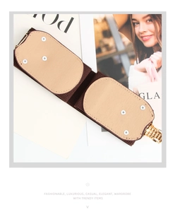 Detail of brown wide elastic waist belt with gold buckle and beige faux leather panels