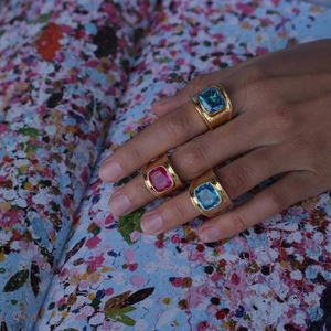 Golden wide band rings with rectangular blue and magenta stones worn by model