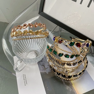 Détail d'un serre-tête de luxe avec cristaux émeraude et roses sur monture dorée