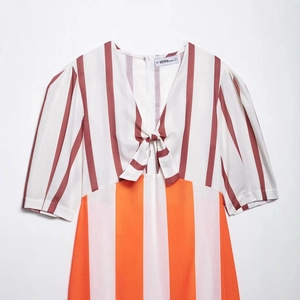 Vertical striped midi dress with tie neckline in white, rust, and bright orange tones