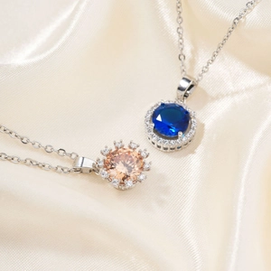 Silver necklace with round champagne and blue zircon pendants on a silk background