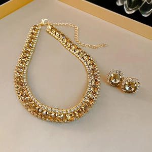 Luxury gold necklace and earrings set with champagne zircon stones on a beige tray