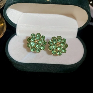 Macro shot of emerald floral stud earrings in a luxury green velvet jewelry gift box