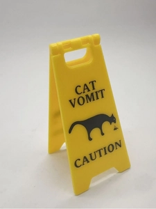 Macro shot of miniature yellow folding Cat Vomit Caution sign on a white background