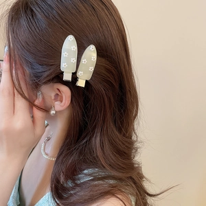 Detail of popsicle shaped green acetate hair clips with daisy flowers on brown hair