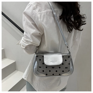 Détail du sac bandoulière argenté à pois noirs, motifs de nœuds et chaîne en métal