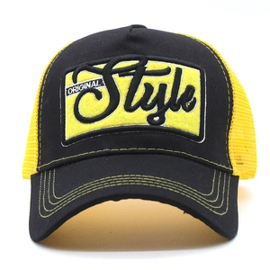 Detail of 3D embroidered patch on breathable black and yellow mesh trucker cap