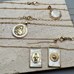 Golden religious medallion necklace set with mother of pearl pendants on a stone surface