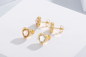 Detail of heart-shaped crystal stud earrings in champagne and clear rhinestone colors