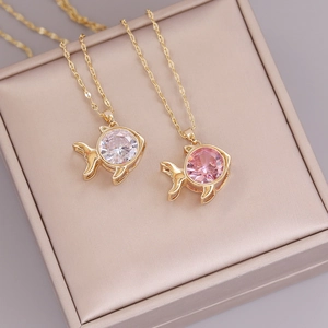 Detail of two gold fish pendants with white and pink cubic zirconia on a gift box lining