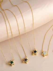Detail of four gold star necklaces with colorful enamel inlays on pink satin