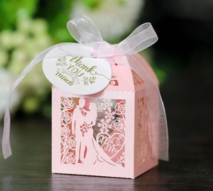 Close-up of pink laser-cut wedding candy box with thank you tag and satin ribbon