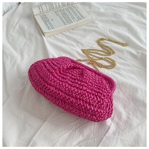 Detailed close-up of rose red woven cloud bag with gold chain on white fabric