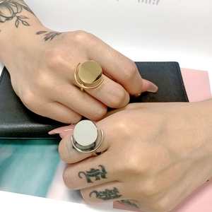 Detail view of gold and silver flat disc rings worn on model hands with artistic tattoos