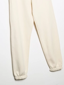 Gros plan sur le pantalon de jogging crème montrant la texture en coton et les poignets