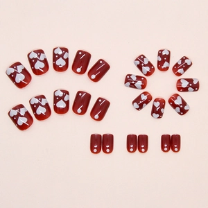 Detail of red press-on nails set featuring white heart and polka dot prints
